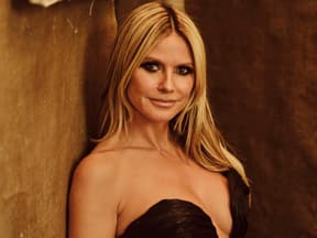 Heidi Klum lehnt an brauner Wand