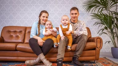 Sarafina und Peter Wollny sitzen mit ihren Zwillingen Emory und Casey auf dem Sofa.