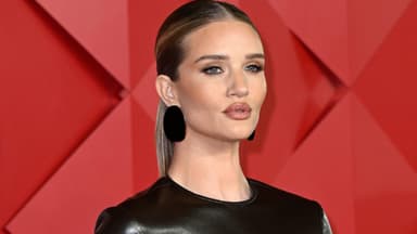 Rosie Huntington-Whiteley mit vollem Mund vor roter Wand