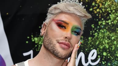 David Lovric mit Regenbogen Make-up und hand an der Wange.