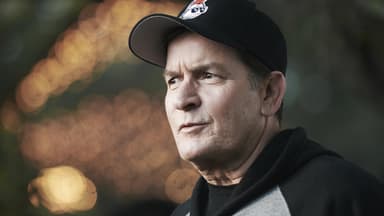 Charlie Sheen trägt eine Cap und einen Hoodie, sieht betroffen zur Seite