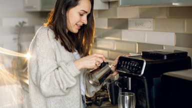 Frau bereitet am Vollautomaten einen Kaffee zu