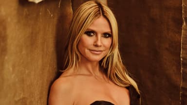 Heidi Klum lehnt an brauner Wand