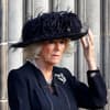 Queen Consort Camilla blickt ernst und fasst sich an den Hut