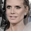 Heidi Klum guckt ernst, im Hintergrund das GNTM-Set