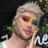 David Lovric mit Regenbogen Make-up und hand an der Wange.