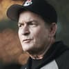 Charlie Sheen trägt eine Cap und einen Hoodie, sieht betroffen zur Seite