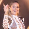 Helene Fischer hebt lächelnd die Hand bei Konzert