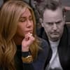 Jennifer Aniston sieht traurig zur Seite, hinter ihr sitzt ein ausgegrauter Matthew Perry, der frustriert aussieht