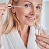 Frau Ü50 trägt Anti-Aging-Serum auf