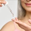 Frau mit Pipette gibt Anti-Aging-Serum auf Finger