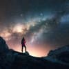 Eine Frau guckt auf einem Berg in den Sternenhimmel