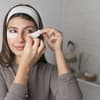 Frau legt weiße Augenpads auf