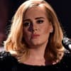 Adele guckt traurig mit Mikrofon.