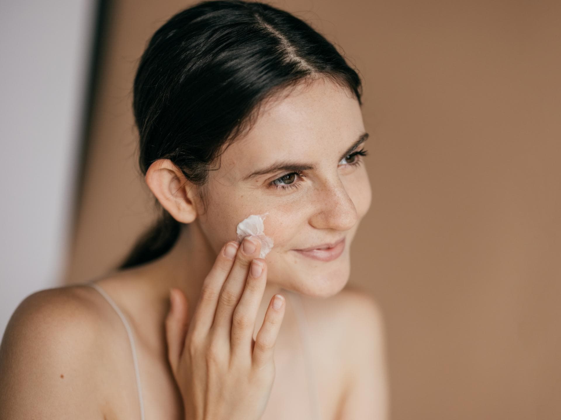 Anti-Aging-Creme reduziert Falten der 7 Jahren Frau trägt Anti-Aging-Creme auf Wangen auf