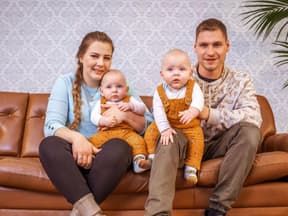 Sarafina und Peter Wollny sitzen mit ihren Zwillingen Emory und Casey auf dem Sofa.