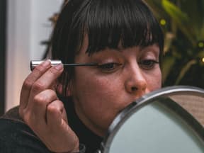 Frau zieht Eyeliner vor Spiegel