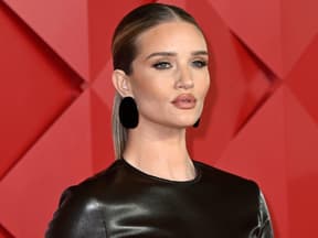 Rosie Huntington-Whiteley mit vollem Mund vor roter Wand