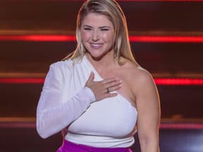 Beatrice Egli lacht und hat die Hand auf der Brust