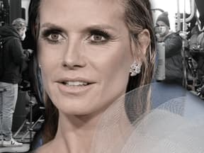 Heidi Klum guckt ernst, im Hintergrund das GNTM-Set