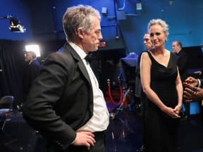 Hugh Grant steht bei den Oscars 2023 Backstage mit den Händen in die Hüfte gestemmt