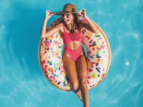 Frau im Badeanzug schwimmt auf Donut