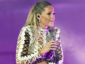 Helene Fischer steht mit Mikrofon auf der Bühne und schaut besorgt ins Publikum