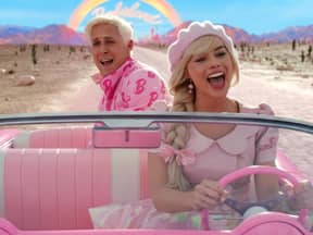 Filmszene: Ryan Gosling als Ken und Margot Robbie als Barbie im pinken Auto lachen