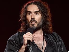 Russell Brand spricht ins Mikrofon und sieht verärgert aus