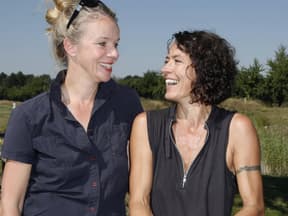 Ulrike Folkerts und Partnerin Katharina Schnitzler sehen sich an und lachen.