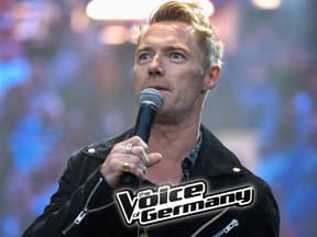 Ronan Keating spricht ins Mikrofon, vor ihm das "The Voice of Germany"-Logo