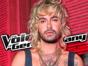 Bill Kaulitz mit ernstem Blick vor "The Voice of Germany"-Logo