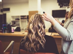 Frau bekommt mit Blowout Bürste Wellen beim Friseur