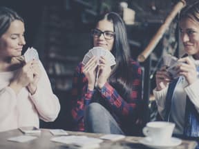 3 Frauen spielen mit karten im Café