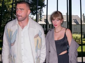 Travis Kelce und Taylor Swift halten Händchen, im Hintergrund sieht man eine Villa hinter einem Gittertor