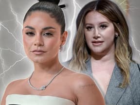 Vanessa Hudgens sieht entschlossen aus, Ashley Tisdale steht mit bedrücktem Gesicht hinter ihr, zwischen ihnen schießen Blitze