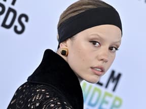 Mia Goth blickt von der Seite in die Kamera, Mund ist leicht geöffnet