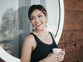 frau hält becher mit kaffee-alternative in der hand und lacht