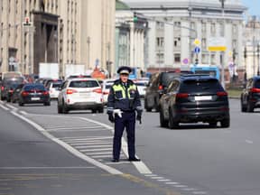 Polizist steht auf der Straße hinter fahrenden Autos