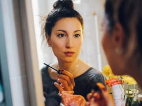 Frau mit Mascara vor Spiegel