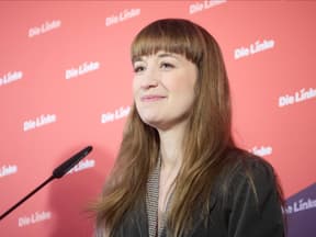 Politikerin Heidi Reichinnek lächelt und steht vor einer Wand mit dem Schriftzug "Die Linke"