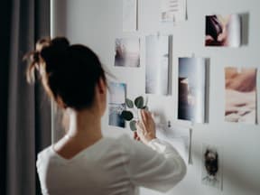 Frau klebt Bilder an ihre Wand