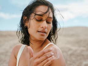 Beste After-Sun-Lotion Frau am Strand cremt sich ein