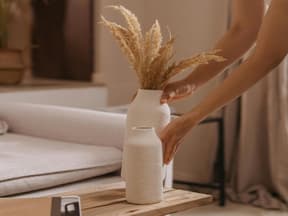 Eine Frau stellt eine Vase auf den Tisch