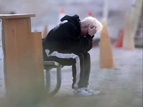 Justin Bieber sitzt auf Bank und hat sein Gesicht in den Händen versteckt.