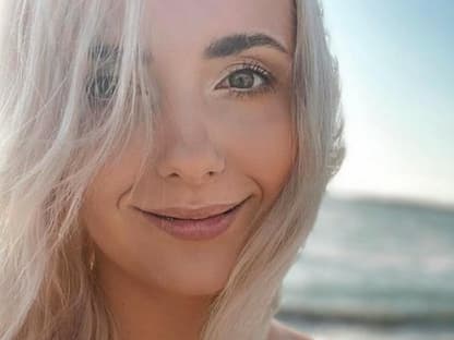 Anna Heiser mit blonden Haaren lächelt am Meer