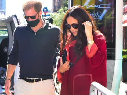 Harry und Meghan schauen auf den Boden, Harry mit Maske