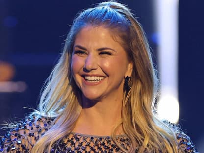 Beatrice Egli lacht und hat ein glitzerndes Oberteil an