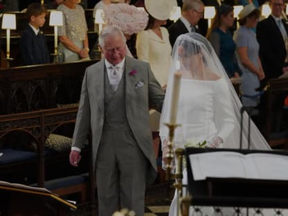 König Charles III. führt Herzogin Meghan zum Altar 2018.