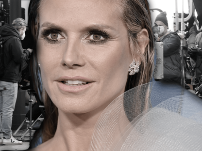 Heidi Klum guckt ernst, im Hintergrund das GNTM-Set